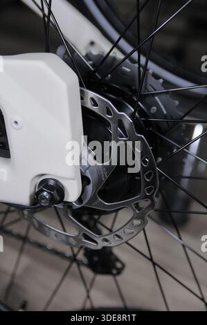 Nahaufnahme eines Hinterrads mit Scheibenbremse und Nabe, moderne mechanische Details für urbane oder elektrische Fahrräder. Stockfoto