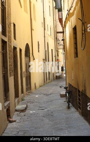Perspektivischer Blick auf eine enge mittelalterliche Straße mit hohen Renaissance-Gebäuden und traditionellen Holzläden im historischen Zentrum von Florenz Stockfoto