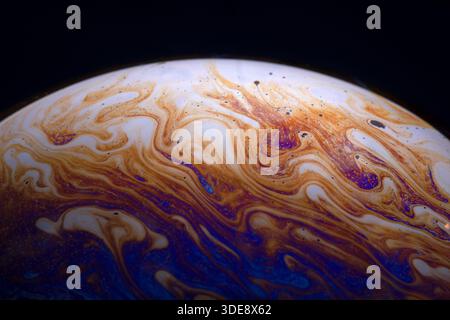 Lebendige abstrakte Muster, die einer planetaren Oberfläche ähneln, mit wirbelnden orange, blauen und weißen Farben auf dunklem Hintergrund. Ideal für Wissenschaft und Stockfoto