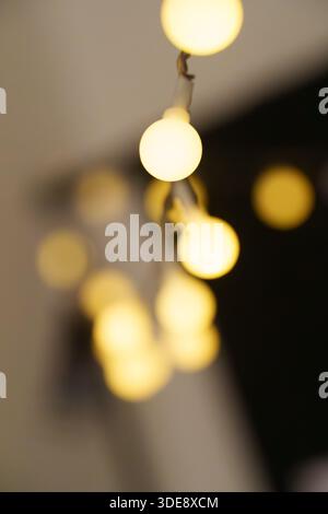 Eine Lichterkette mit einer weißen Glühlampe. Die Lichter sind an und leuchten. Die Lichter hängen an einer Wand Stockfoto