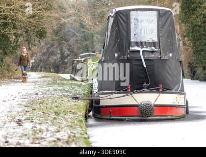 Stourbridge, Großbritannien. Januar 2026. Wetter in Großbritannien: Die Menschen trotzen den eiskalten Bedingungen und machen mit ihren Hunden einen Morgenspaziergang vorbei an Schmalbooten, die fest im Eis entlang eines Stourbridge-Kanals eingesperrt sind, nachdem die nächtlichen Temperaturen wieder auf –5 °C fielen und die Midland Waterways fest gefriert haben. Quelle: Lee Hudson/Alamy Live News Stockfoto