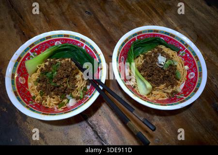 Zwei Schüsseln Ramen-Nudeln, japanisches Essen mit schwarzen Essstäbchen auf einem Holztisch. Stockfoto