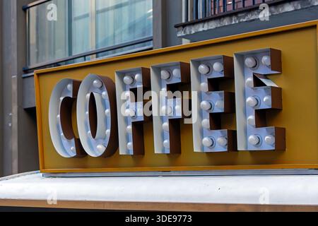 Glühbirnen, Kaffeebild, das an der Gebäudefassade in der Stadtstraße hängt Stockfoto
