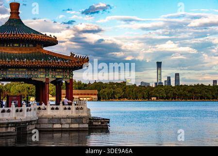 Traditionelle chinesische Pavillonarchitektur im Beihai Park mit Blick auf den See in Peking, China, mit der modernen Skyline von Peking CBD in der Ferne. Stockfoto