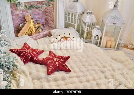 Eine gemütliche Winterszene mit einer weichen Decke, dekorativen Kissen und Laternen, mit einem Kamin im Hintergrund Stockfoto