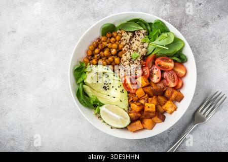 Gesunde vegane Mittagsschale. Avocado, Quinoa, Süßkartoffeln, Tomaten, Spinat und Kichererbsen Gemüsesalat. Draufsicht Stockfoto