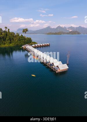 Erkunden Sie das ruhige Wasser des Cheow Lan Lake in Khao Sok, Thailand. Schwimmende Bungalow-Flöße mit Touristen in einem Kajak Stockfoto