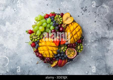 Köstliche Platte mit Früchten und Beeren. Mango, Kiwi, Erdbeere, Traube, Kirsche, Heidelbeere, Pfirsich und Passionsfrucht, Blick von oben Stockfoto