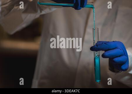 Chemiewissenschaftlerin, die Experimente im Labor macht. Pipette, die farbenfrohe Lösung in Röhrchen, medizinischer abstrakter Hintergrund hinzufügt. Stockfoto