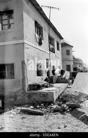 Auf der Terrasse eines heruntergekommenen Wohnhäuser am Strand von Durrës verarbeitet eine Frau Schafwolle, hinter ihr steht ein junger Mann neben einer behängten Wäscheleine, Albanien 1980. Auf der Terrasse einer baufälligen Wohnung am Strand von Durrës verarbeitet eine Frau Schafwolle, hinter ihr steht ein junger Mann neben einer Wäscheleine, die mit Wäsche gehängt wurde, Albanien 1980. Stockfoto