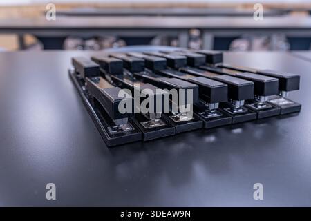 Nahaufnahme von 14, 14 schwarzen Heftern auf einem schwarzen Schreibtisch. Stockfoto