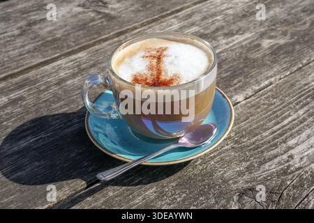 Cappuccino-Kaffee auf Holztisch im Garten. Erfrischendes heißes Getränk. Koffeingetränk Stockfoto