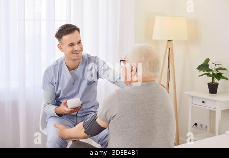 Die Krankenschwester misst den Blutdruck eines kranken älteren, Reifen männlichen Patienten, der ihn zu Hause besucht. Stockfoto