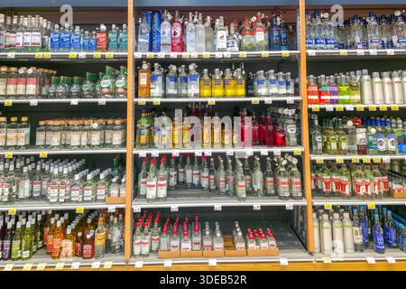 Liepaja, Lettland- 04. Januar 2026: Alkoholbereich im Supermarkt mit verschiedenen Wodka-Marken in Regalen mit Preisschildern und Sicherheitsflaschenverschlüssen Stockfoto