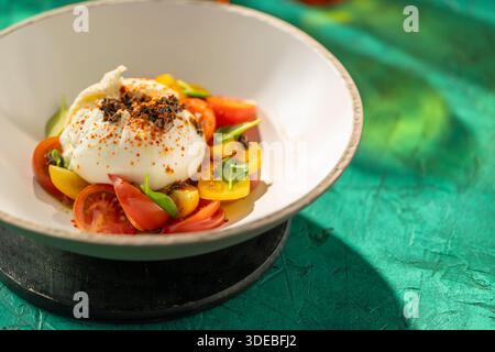 Gourmet-Burrata-Käsesalat mit bunten Kirschtomaten und Basilikum Stockfoto