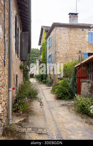 Enge Dorfgasse mit traditionellen Steinhäusern und bunten Blumen in Saint Jean de Cole, Frankreich Stockfoto