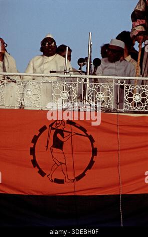 Jagjivan RAM und Morarji Desai bei einem öffentlichen Auftritt auf einer Tribüne mit Mikrofonen, begleitet von weiteren Personen. Blick von unten auf eine dekorierte Balustrade mit Banner. Indien, 1970er. Stockfoto