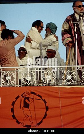 Jagjivan RAM und Morarji Desai auf einer Tribüne bei einer öffentlichen Veranstaltung, umgeben von weiteren Personen, Mikrofonen und einer dekorativen Balustrade mit Banner. Indien, 1970er. Stockfoto