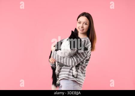 Frau mit ihrem süßen Border Collie Hund auf rosa Hintergrund Stockfoto
