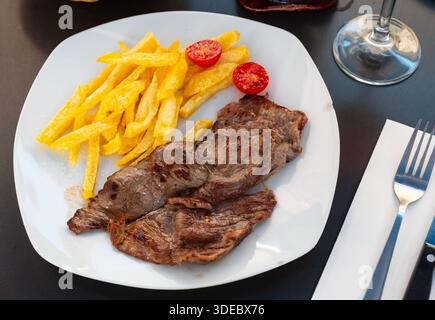 Kalbsentrecote mit Beilage aus Pommes frites und frischen Tomaten Stockfoto