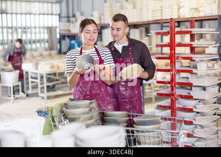Kollegen in der Keramikwerkstatt, die Slipcast-Keramik untersuchen und diskutieren Stockfoto