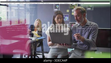 Ich überprüfe zwei Kollegen in Geschäftskleidung, die auf den Laptop im Besprechungsraum zeigen, mit Code-Overlay Stockfoto