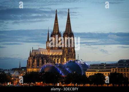 Nachtansicht auf den Kölner Dom, den blau beleuchteten Musical Dome und das EASA-Gebäude am Rheinufer in Deutschland bei Dämmerung Stockfoto