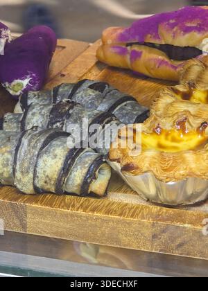 Köstliches Croissant aus schwarzer Holzkohle mit Butterkruste, herzhafter Torte, süßem Donaubrot auf Holztablett, mit frisch gebackener Bäckerei-Auswahl mit Appeti Stockfoto