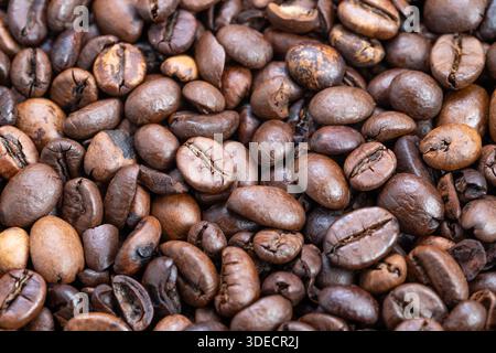 Close-up geröstete Kaffeebohnen verteilt über Sackleinen, warme Glanztöne, unterschiedliche Röststufen, reichhaltige Aromaempfehlung, ideal für Café-Branding, Verpackung Stockfoto
