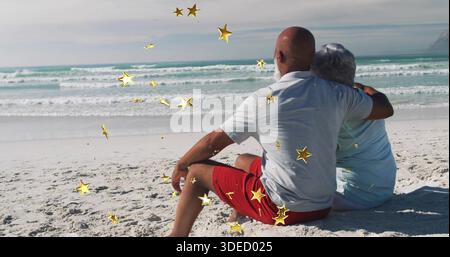 Sitzendes, reifes Paar, das mit Blick auf das Meer am weißen Strand in Sommerkleidung, goldenen Sternen, Kopierraum umarmt Stockfoto