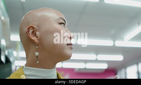 Kahle asiatische Frau, die Produkte in einem hell beleuchteten Geschäft sucht Stockfoto