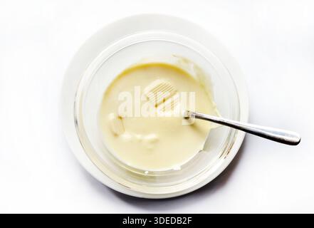 Geschmolzene weiße Schokolade in einer Glasschale isoliert auf weißem Hintergrund. Draufsicht. Stockfoto