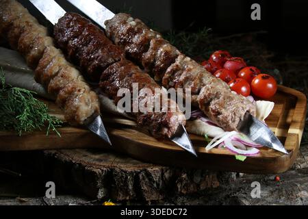 Nahaufnahme eines traditionellen kaukasischen Gerichts – gegrilltes Hackfleisch (lula Kebab oder Shish Kebab) auf Metallspießen. Mit Kebabs aus Chi Stockfoto