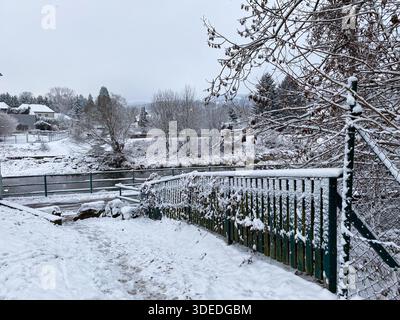 Verschneite Holzzaun in der Nähe eines fließenden Flusses im Winterpark Stockfoto