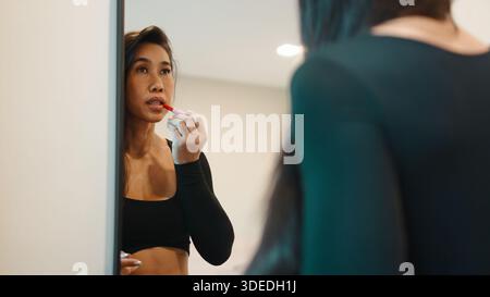 Befähigte Frau, die Lippenstift aufträgt und Selbstbewusstsein widerspiegelt Stockfoto