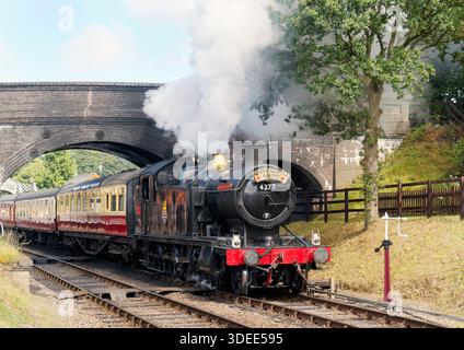 Ein Zug mit der ehemaligen Great Western RLY 2-8-0T Dampflokomotive 4277 fährt von der Weybourne Station an der North Norfolk Railway mit einem Zug nach Holt ab. Stockfoto