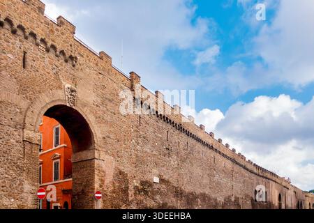 Blick von unten auf die Mauern des Passetto di Borgo mit Steinbogen und rotem Gebäude in Rom, Italien. Stockfoto