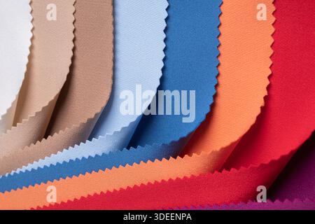 Studio-Nahaufnahme mit farbenfrohen Stoffmustern in geschwungenen Falten, die lebendige und pastellfarbene Töne mit gepinkten Kanten zeigen. Ideal für Textildesign... Stockfoto