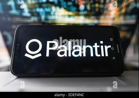 In dieser Fotoabbildung wird auf einem Smartphone oben auf einem Laptop ein Palantir-Logo angezeigt. Stockfoto