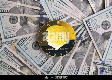 KIEW, UKRAINE - 13. DEZEMBER 2025 Trump Goldmünze auf großen Mengen von US-Dollar-Banknoten Stockfoto