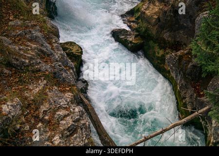 Ein schneller Gebirgsbach fließt durch einen schmalen felsigen Canyon und erzeugt weißen Schaum und türkisfarbenes Wasser. Stockfoto