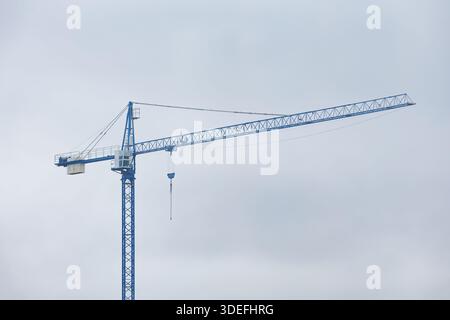 Baukran gegen Himmel. Baukran gegen bewölkten Himmel, industrielle Infrastruktur und städtebauliches Konzept mit Kopierraum. Stockfoto