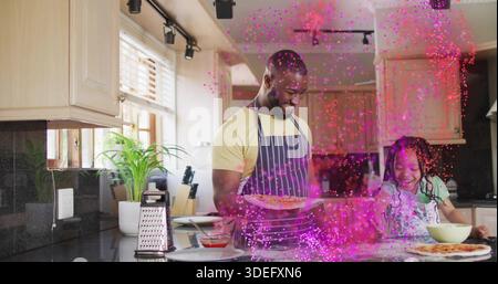 Kochen Vater und Tochter mit Schürzen, die Pizzen zubereiten, Tablett und Schüssel halten Stockfoto