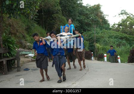 Träger tragen eine ältere Frau den Berg hinauf zum Golden Rock Tazaungdaing Festival auf einer traditionellen Bambustrage, die manchmal als hölzernes Streichbett oder einfach nur als Trage bezeichnet wird, Myanmars Festival of Lights. Ein buddhistisches fest am Ende der Regenzeit, wo der heilige Goldene Felsen zu einem wichtigen Wallfahrtsort wird. Kyaiktiyo, Mons State, Myanmar 9. November 2011 2010, HOMER SYKES. Stockfoto