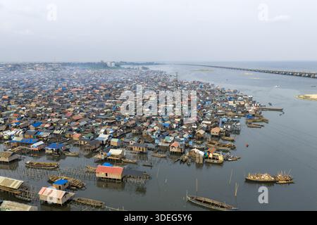 Aus der Vogelperspektive auf ein weitläufiges Slumviertel, wo Holzhäuser aus dem Wasser ragen, ein Wandteppich aus Wellblechdächern unter einem trüben Himmel, Yaba, Lagos, Niger Stockfoto