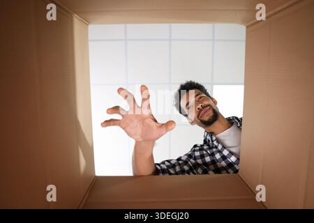 Mann, der in den Karton greift, Blick aus dem Inneren des Pakets Stockfoto