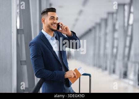 Ein Gutaussehender Geschäftsmann Aus Dem Nahen Osten, Der In Der Airport Lounge Auf Dem Handy Telefoniert Stockfoto