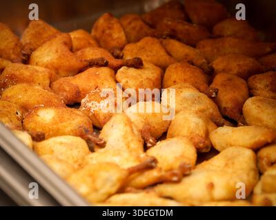 Scheuerschale gefüllt mit goldgebratenen Vorspeisen, die bei einem Indoor-Buffet oder Catering-Event warm gehalten werden. Stockfoto