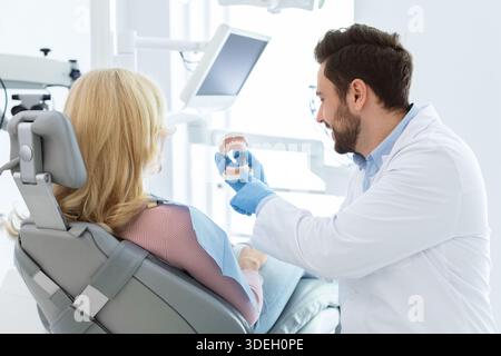 Beraded Doctor Zahnarzt zeigt jow Miniatur dem Patienten Stockfoto