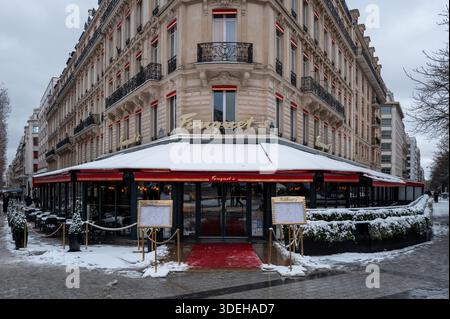 Paris, Frankreich - 7. Januar 2026: An einem Wintertag wird die Fassade des Pariser Restaurants Fouquet mit einer schneebedeckten Terrasse, roten Markisen, Speiseständen und einer historischen Steinfassade gezeigt. Stockfoto